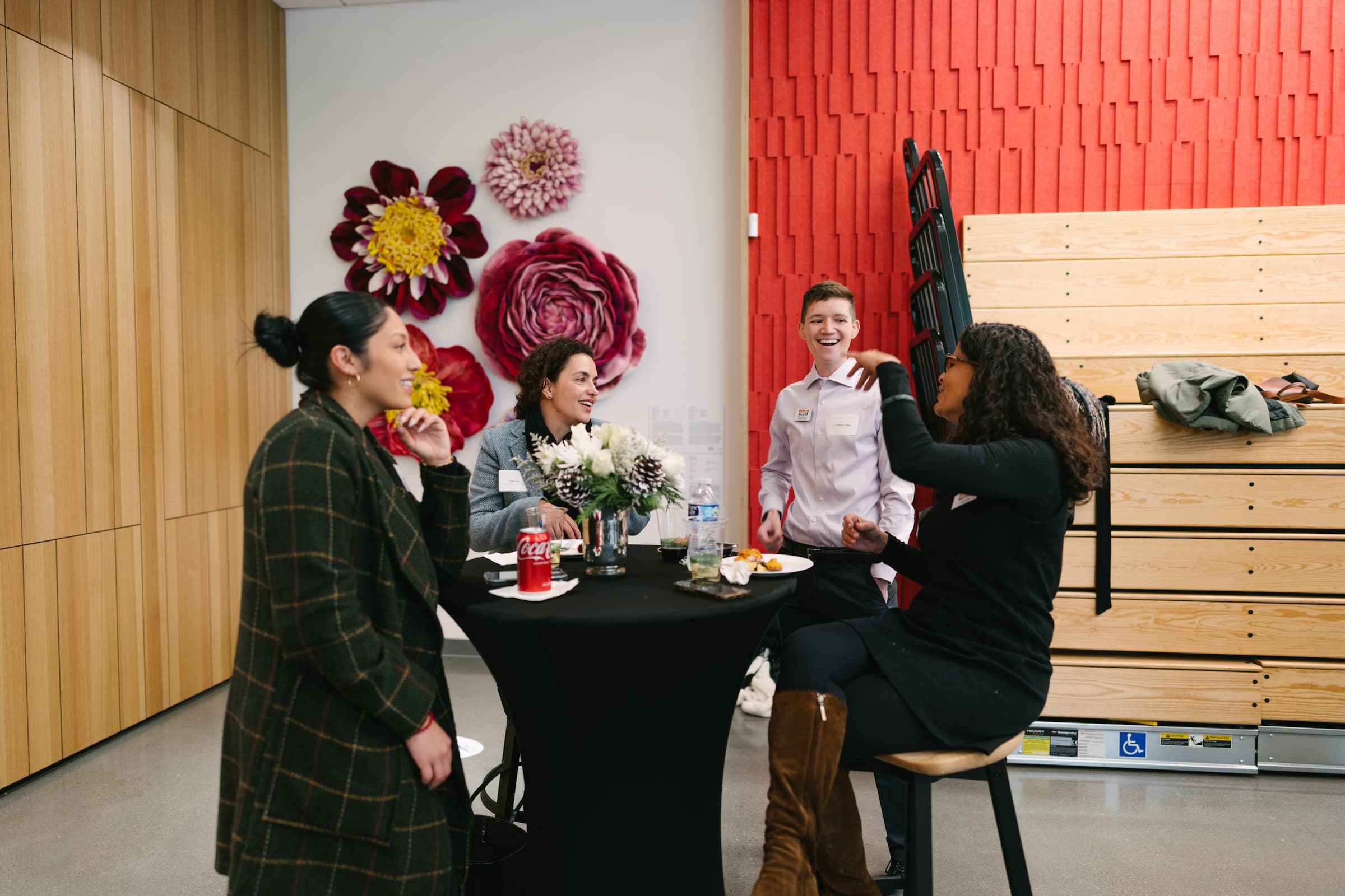 Four event attendees stand around a table talking and laughing.