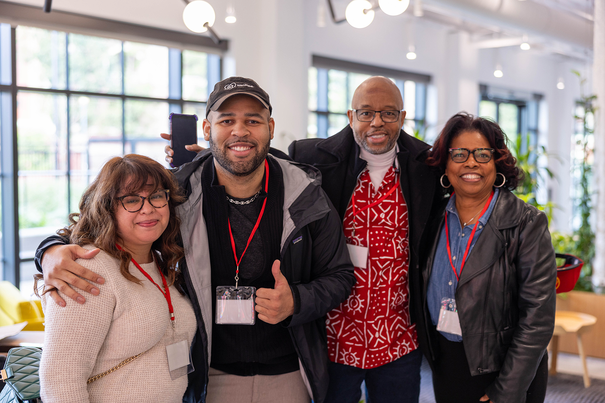 Four co-workers stand together and smile for the camera.